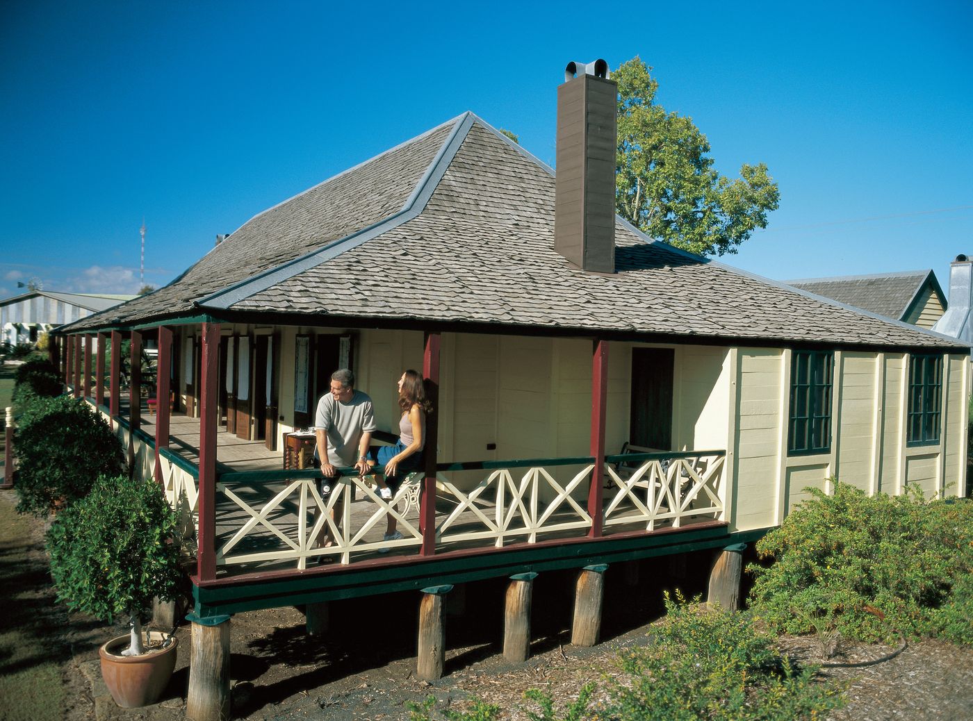 A couple on the verandah of a heritage cottage at the Capella Pioneer Village